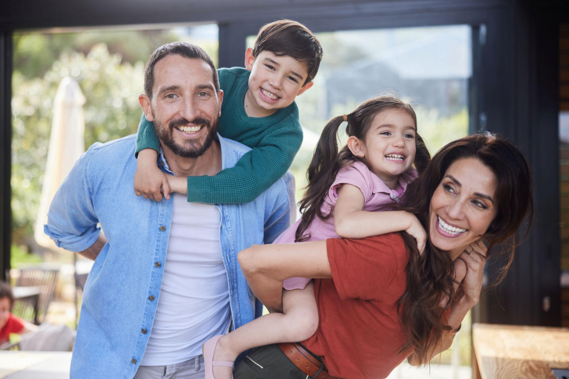 A warm family moment — parents and grandparents hugging young children on a cozy couch.